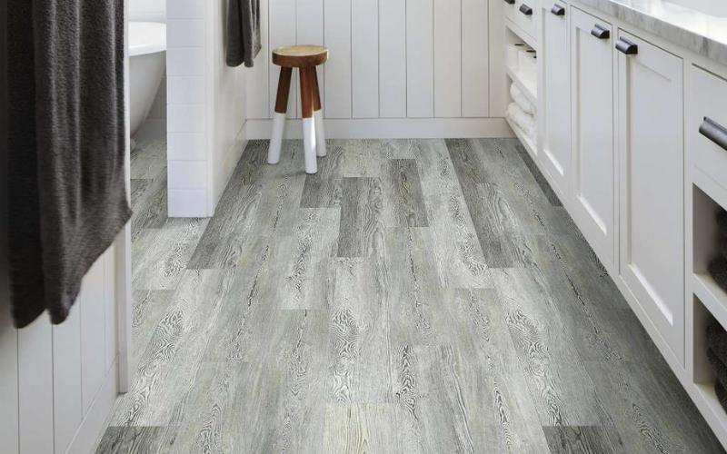 Grey toned wood flooring with white shiplap and a stool with white legs and natural wood top |Grey or Natural Colour Flooring Trends