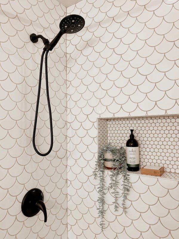A photo of a shower with modern white tile, and black shower head. (Image source: Ceratec/The Everyday Home).