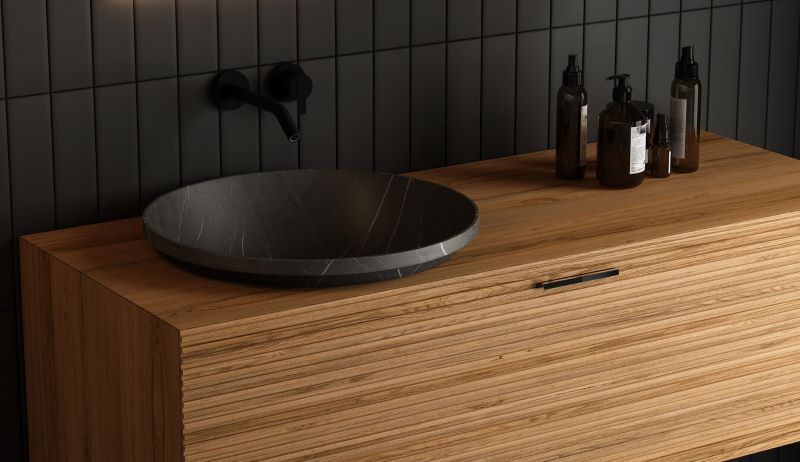 A phot of a wood vanity with a black sink in a bathroom.
